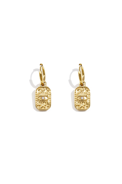 Pair of gold hoop earrings with rectangular charm featuring an embossed eye design and central rhinestone on white background