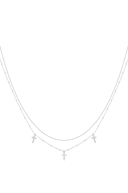 Silver layered necklace with two fine chains and three small cross pendants displayed on a white background