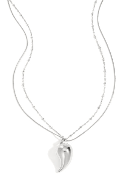 Silver layered necklace with a curved droplet pendant on a white background featuring delicate mixed chains