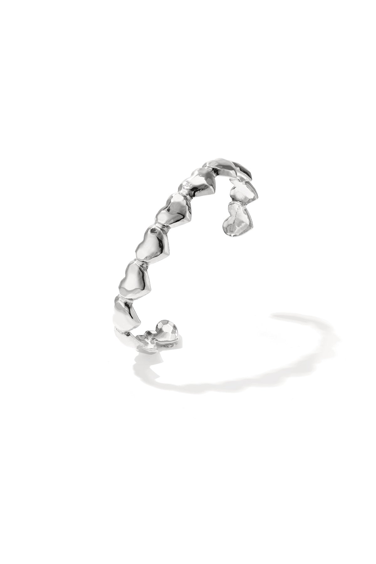 Silver dented heart cuff bracelet with open design on white background