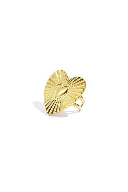 Close-up of a gold heart-shaped statement ring with sunburst texture on a white background