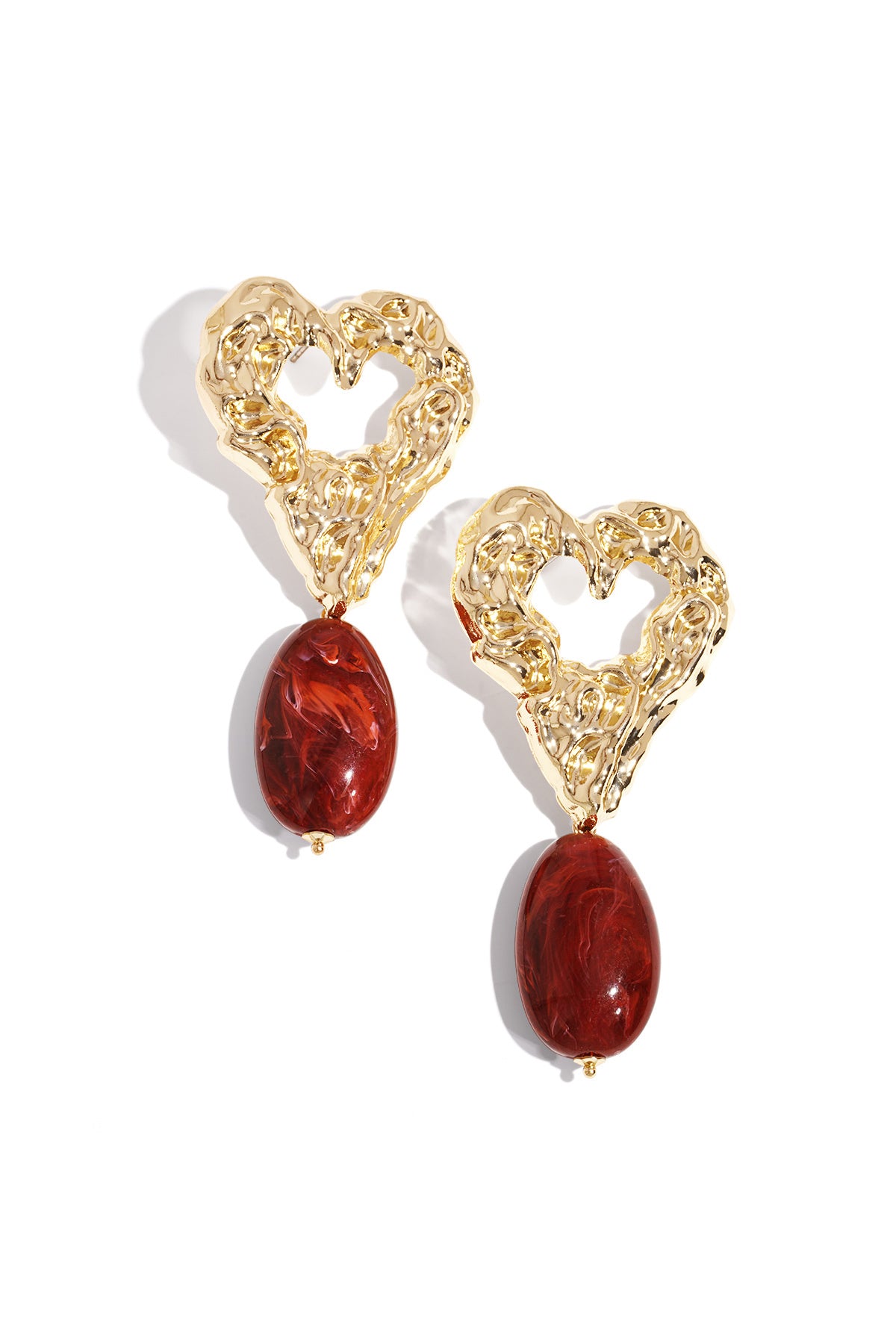 Pair of gold-tone textured heart earrings with deep red marbled resin drop pendants on white background
