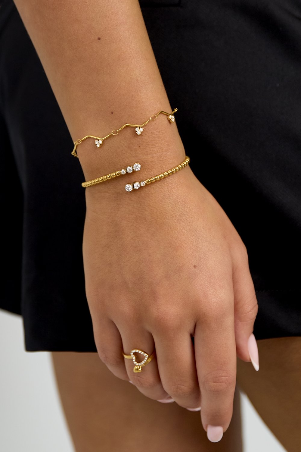Gold Zigzag Charm Bracelet featuring delicate heart-shaped crystals on a thin chain, worn on a model's wrist.