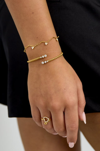 Gold Zigzag Charm Bracelet featuring delicate heart-shaped crystals on a thin chain, worn on a model's wrist.