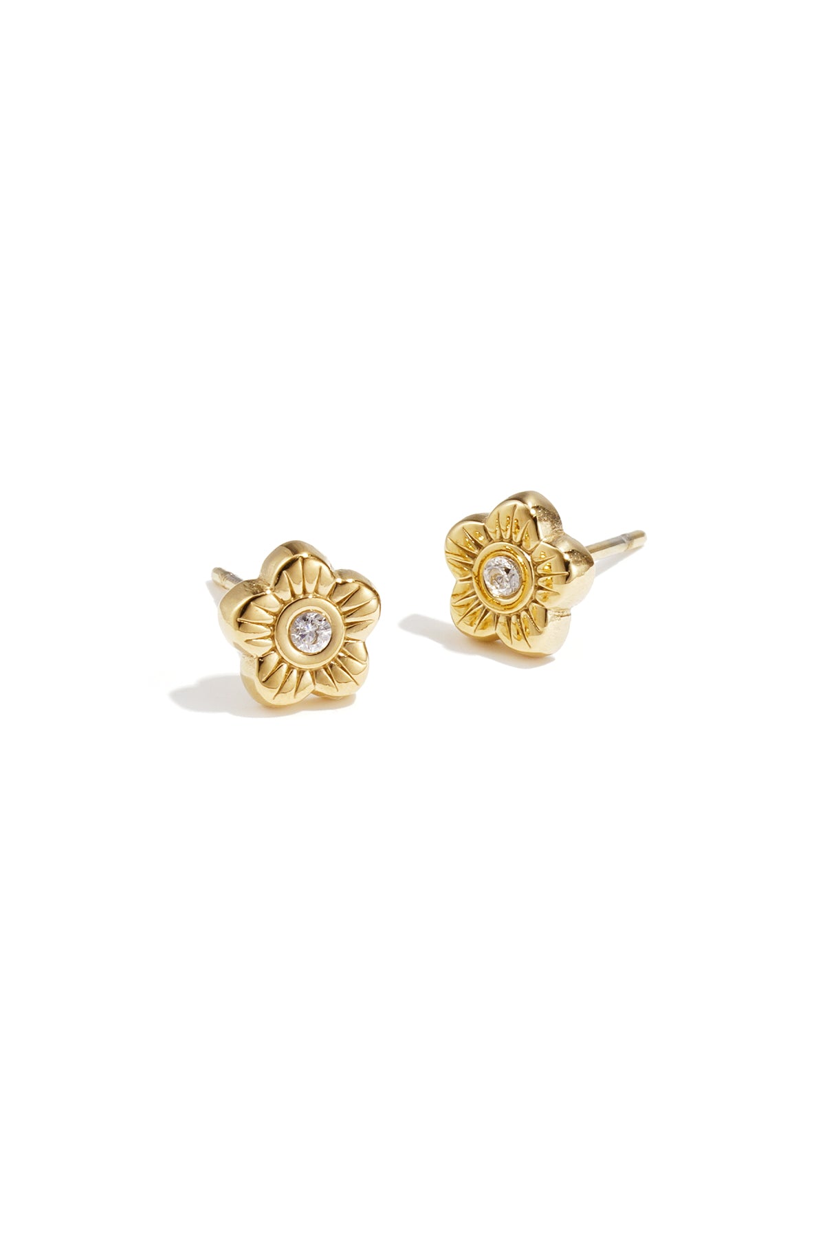Close-up of gold flower-shaped stud earrings with rhinestone center on white background