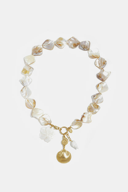 Seashell charm statement necklace with natural shell beads and dangling gold and white shell charms displayed on a white background