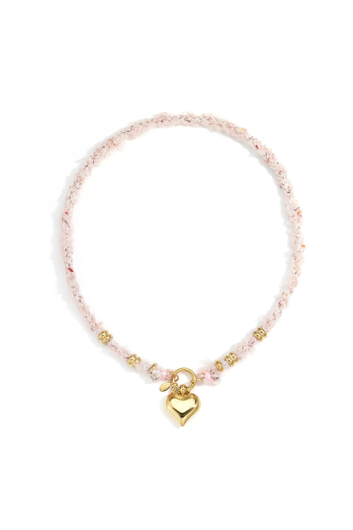 Gold heart pendant necklace with soft pink textured wool rope chain and gold rings laid flat on white background