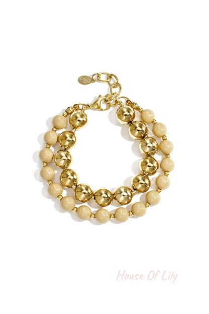 Double layered bracelet with cream acrylic and gold-tone beads on white background
