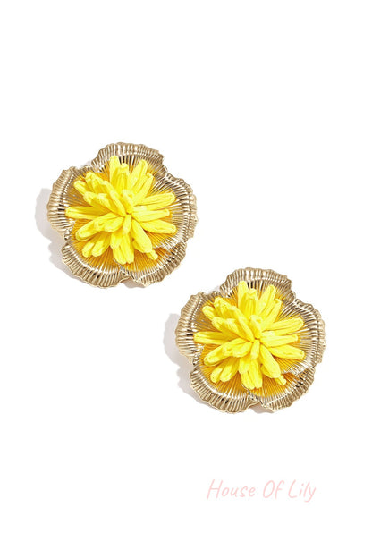 Pair of yellow 3D raffia flower stud earrings with gold-tone metal framing on white background