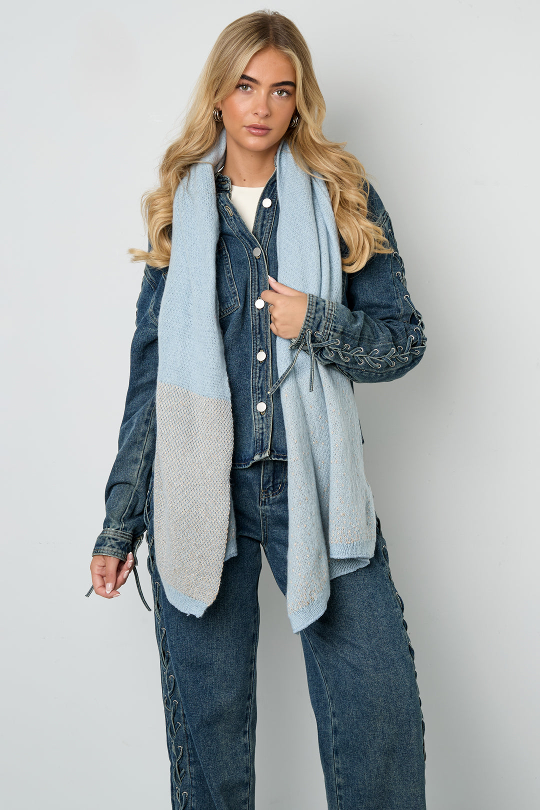 Model showcasing the light blue scarf worn long over denim outfit, hands in pockets