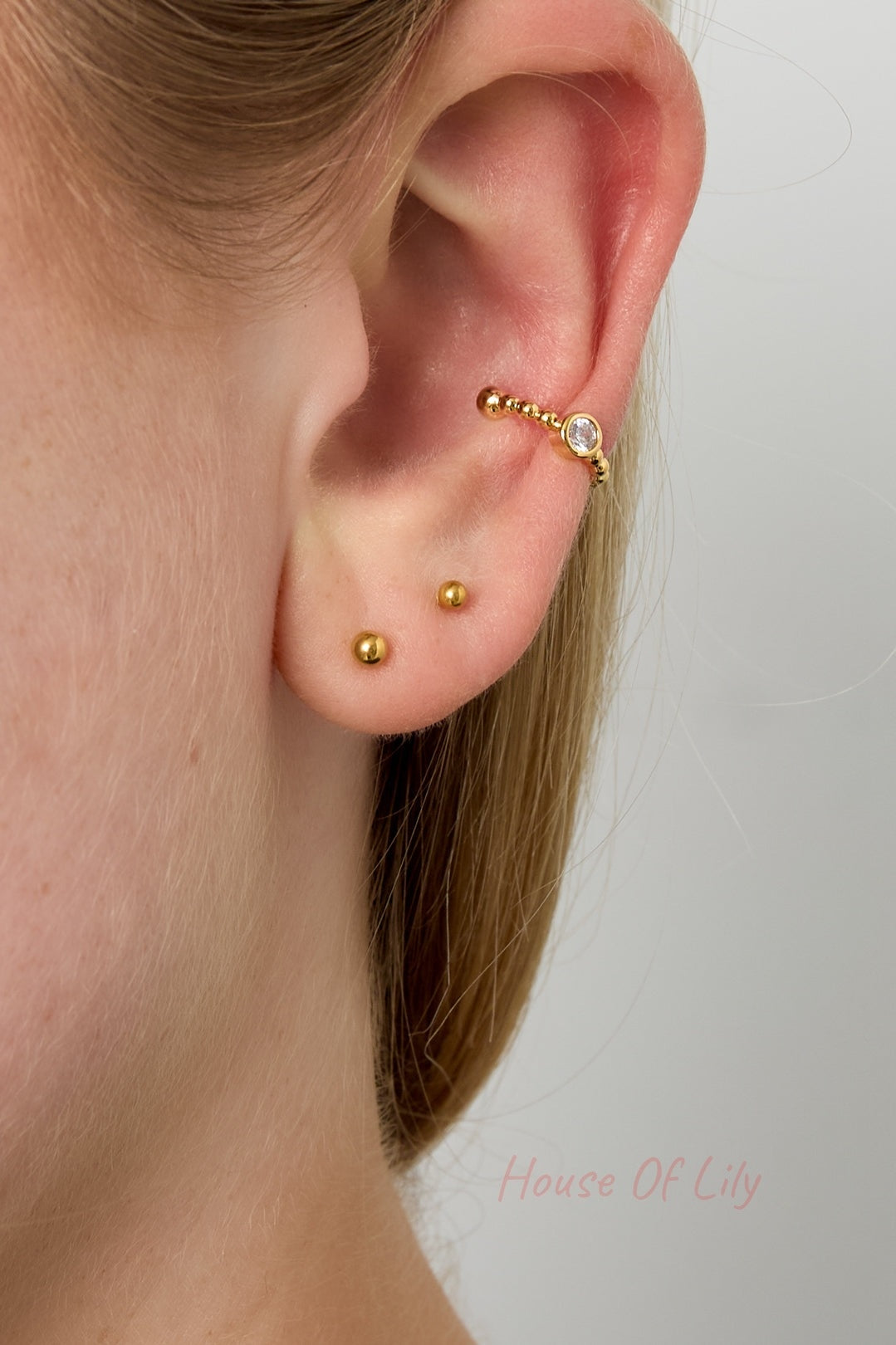 Side profile of a woman wearing the gold beaded crystal ear cuff on upper ear, paired with small gold stud earrings