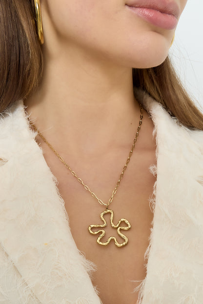 Detailed shot showing the gold floral pendant necklace on a woman's neck, highlighting the hammered texture of the pendant