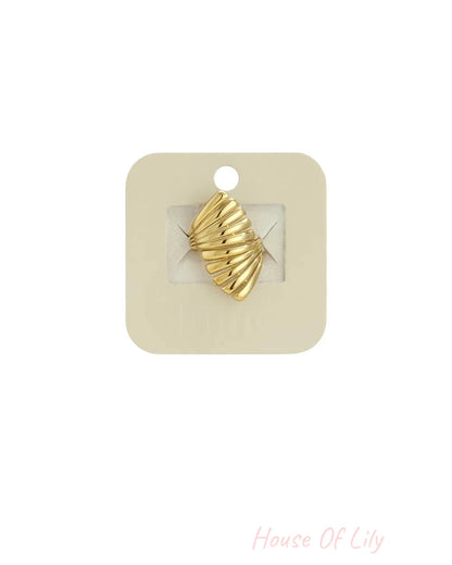 Gold metal ring shaped like a stylized fan or shell, displayed on a square card.