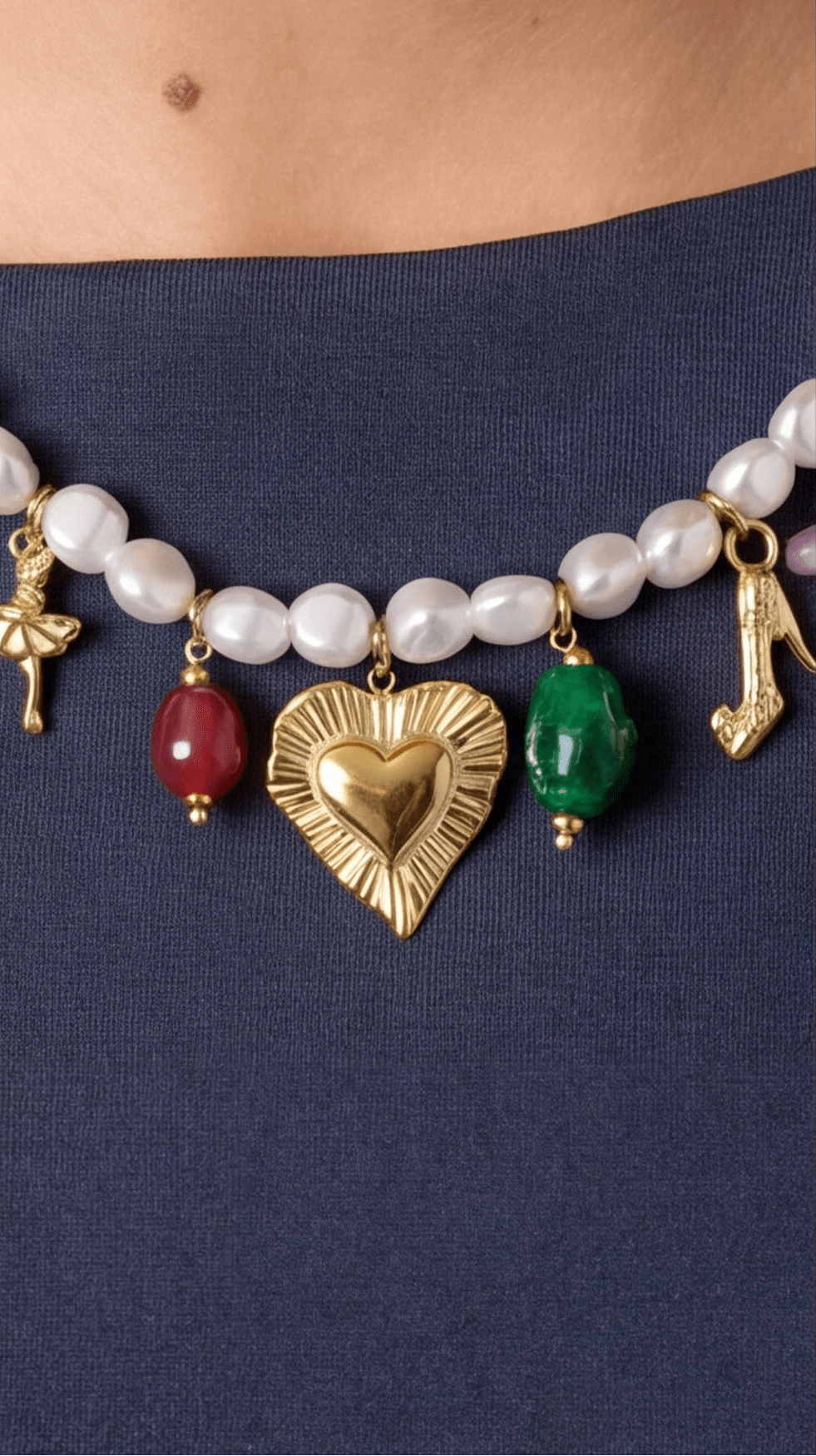 Pearl multi-charm necklace featuring gold charms (heart, dancer, shoe) and red and green stone beads.