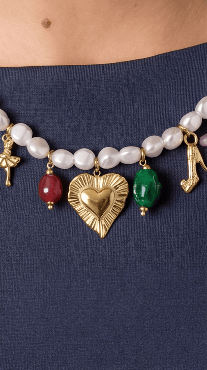 Pearl multi-charm necklace featuring gold charms (heart, dancer, shoe) and red and green stone beads.