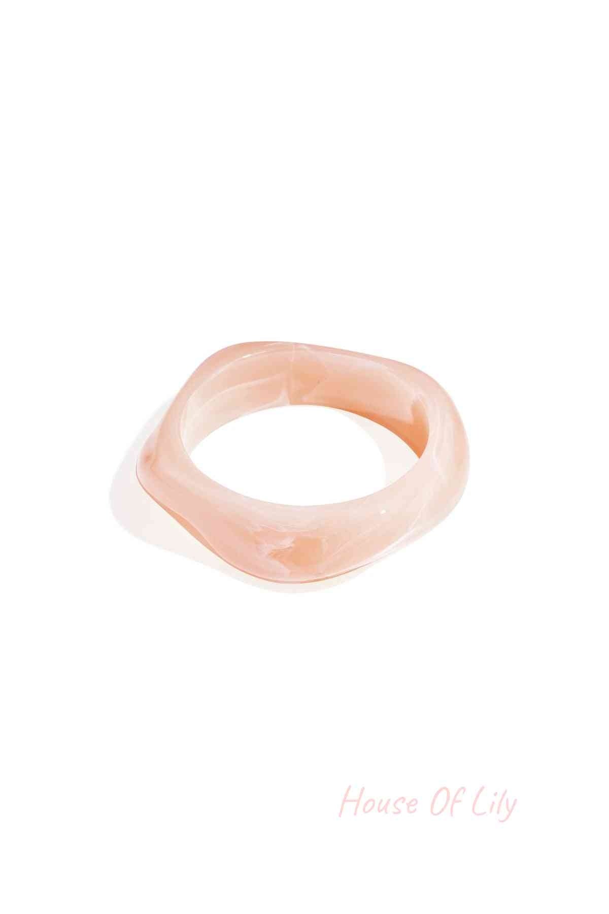 Single ivory white marbled acrylic wavy square bangle on a white background