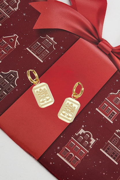 Gold drop earrings displayed on a red festive packaging with canal house patterns and a bow.