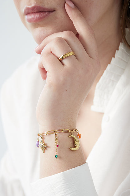 Hand model wearing the gold moonlight charm bracelet paired with a textured gold pattern ring on finger and a white blouse