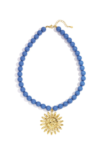Blue beaded necklace with gold sun pendant laid flat showing clasp and pendant details