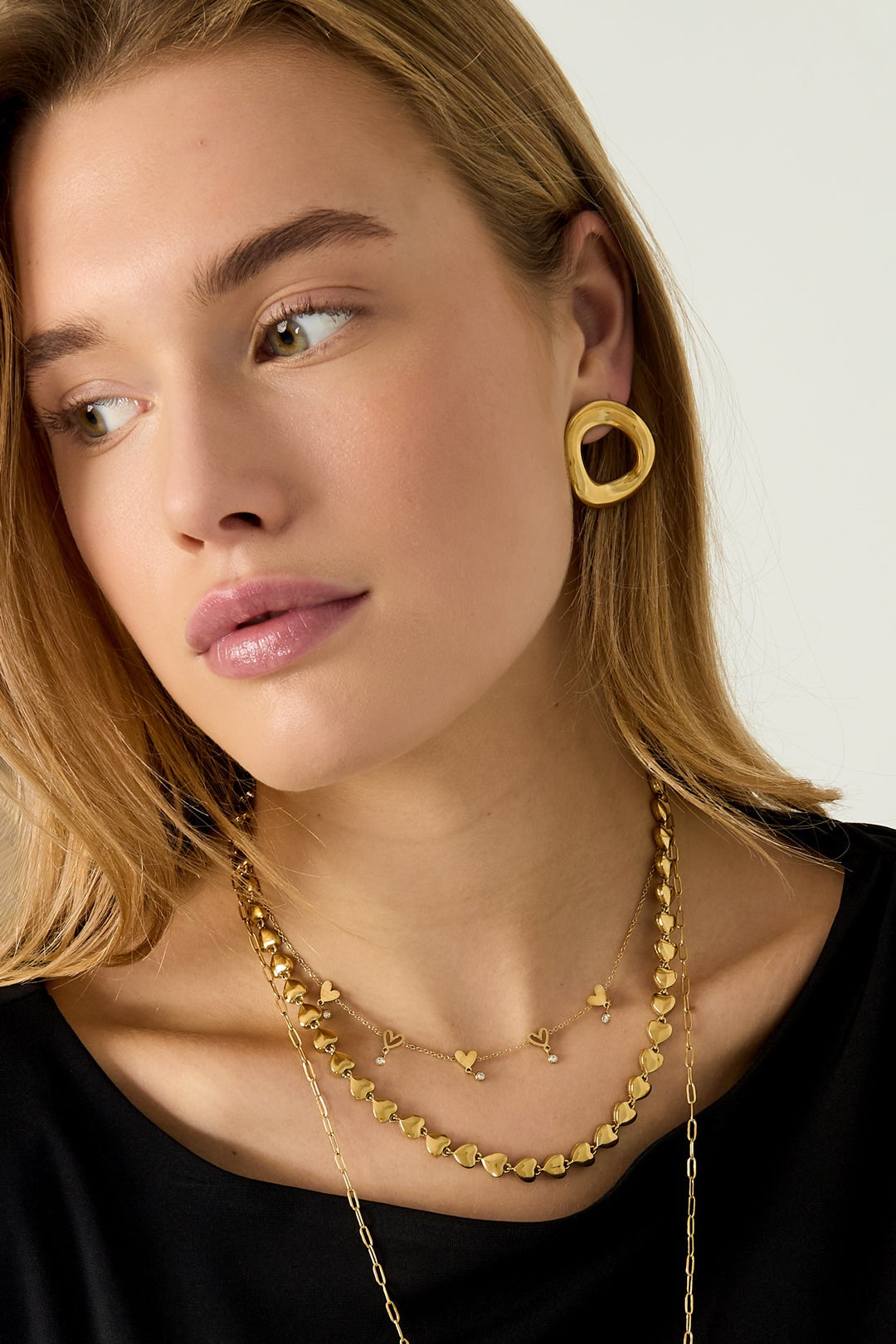 Side angle close-up of model wearing the layered gold necklaces and textured gold earrings highlighting necklace details