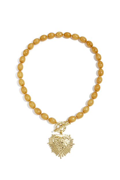 studio shot of baby blue beaded necklace with gold textured heart pendant and toggle clasp