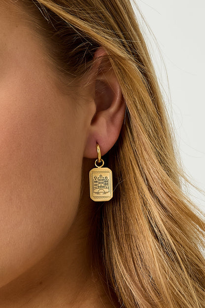 Close-up model image highlighting the detailed design of the gold Amsterdam Canal House Earrings on a woman.