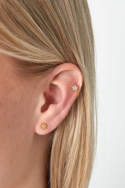 Model wearing gold floral crystal stud earring and matching gold floral crystal ear cuff on upper ear