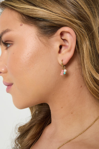 Side profile of a woman wearing gold hoop earring with pink, turquoise, and pearl beads highlighting youthful and minimal design