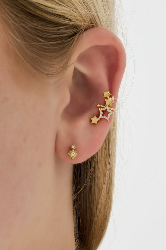 Close-up of gold star ear cuff worn on woman's ear with additional stud earring