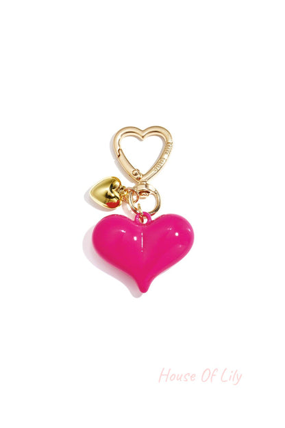 Single hot pink acrylic heart bag charm with gold heart clasp and mini gold heart pendant on white background