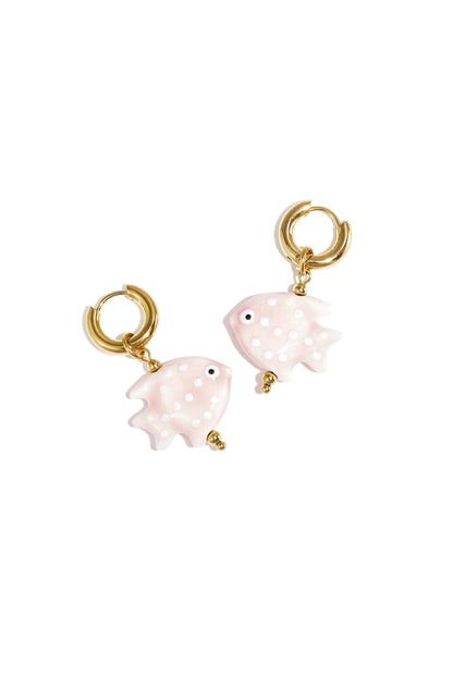 Pair of gold hoop earrings featuring soft pink fish-shaped charms with white polka dots on white background