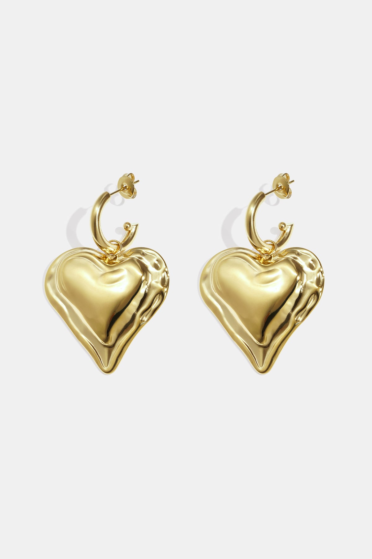 Close-up of chunky gold heart hoop earrings with rippled textured heart charms on white background
