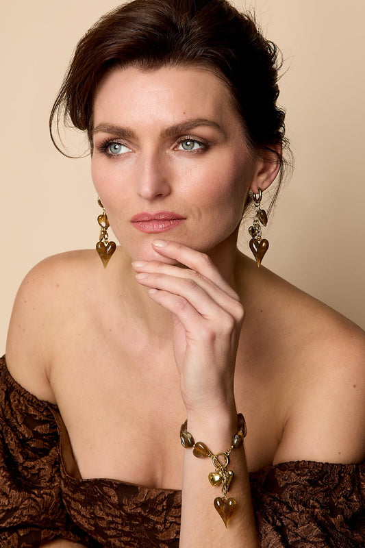Woman wearing amber brown marbled heart-shaped acrylic bead bracelet and matching earrings, posing thoughtfully