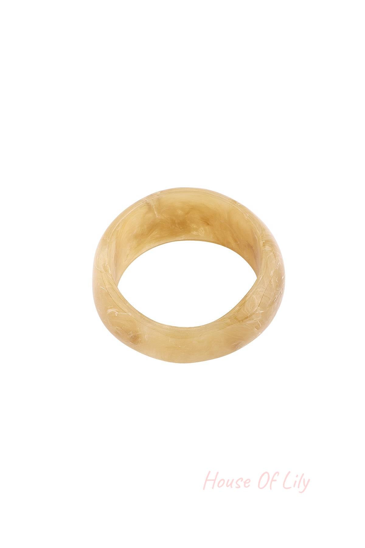 Close-up of light beige marbled resin bangle bracelet on white background