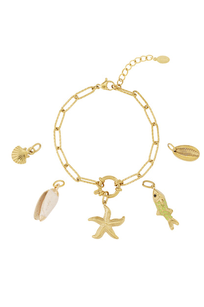 Gold-plated charm bracelet with ocean-themed charms including starfish, shell, fish, and cowrie shell arranged on a white background