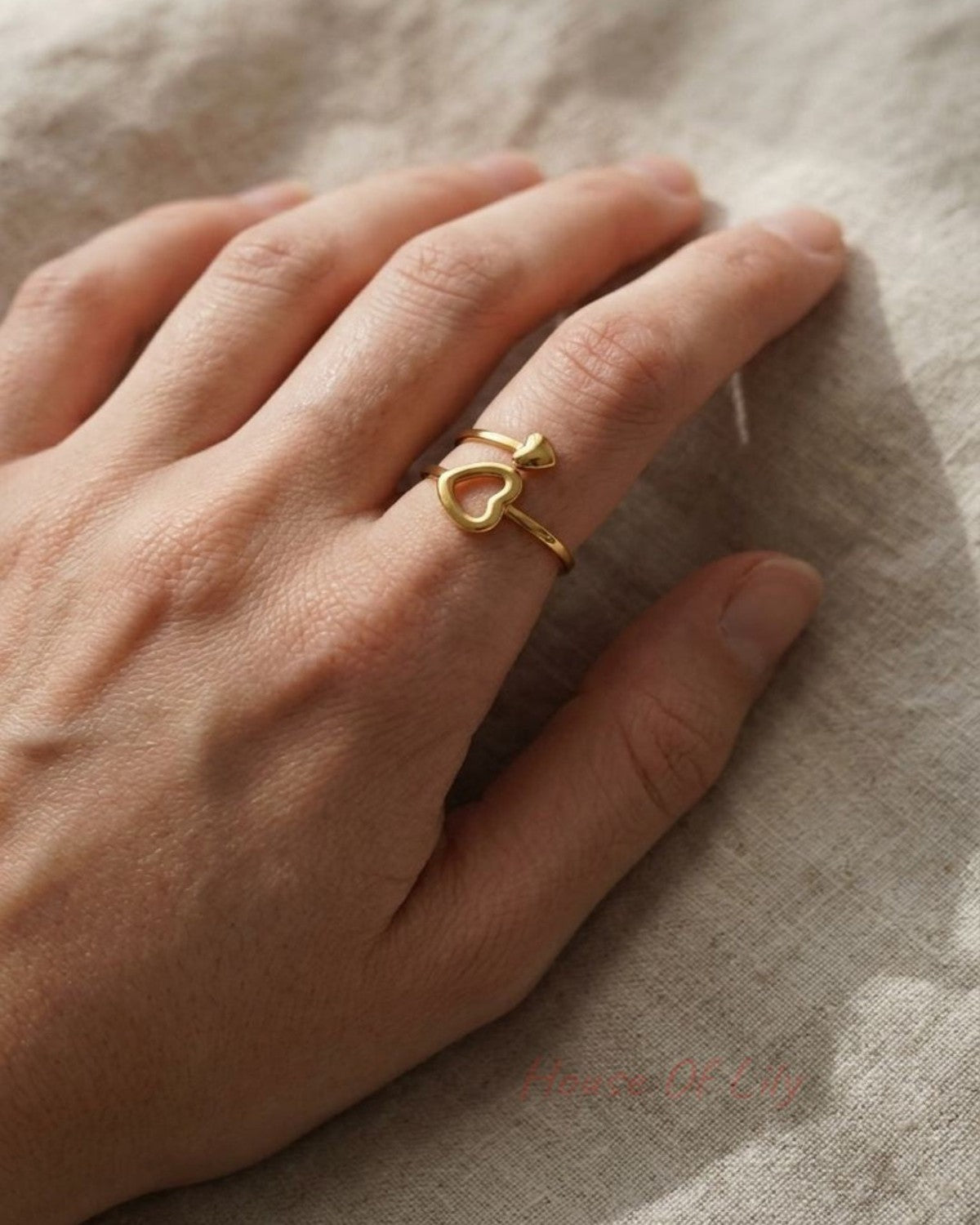 Full-body shot of a feminine hand wearing the Split Heart Mood ring on a soft fabric, showcasing its delicate adjustable band.