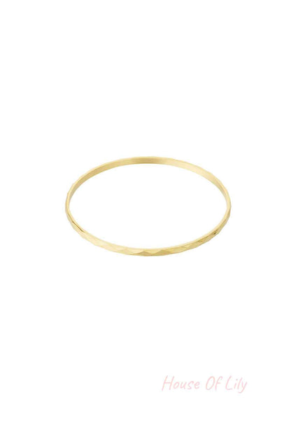 Single gold facet textured bangle bracelet on white background