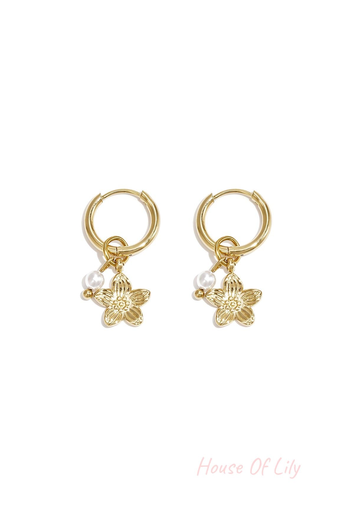 Pair of gold hoop earrings with dangling gold flower charm and small white pearl bead on white background