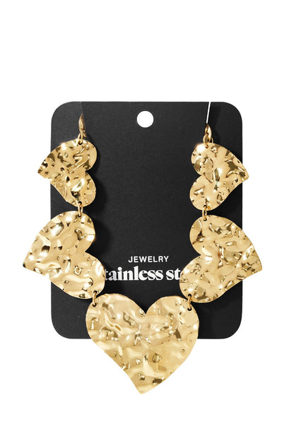Gold-tone stainless steel drop earrings featuring multiple linked, hammered-texture heart shapes on a display card.