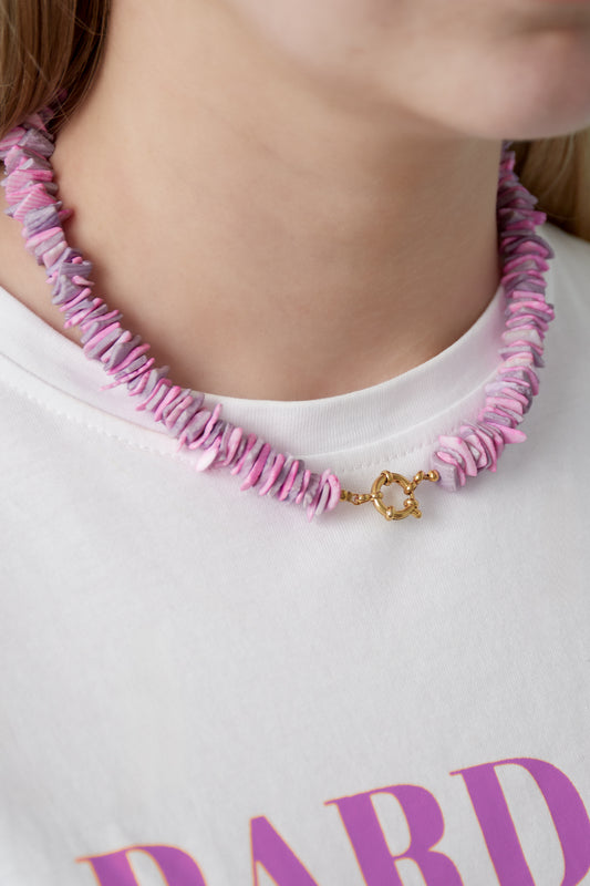 Close-up of pink shell choker necklace worn over white T-shirt