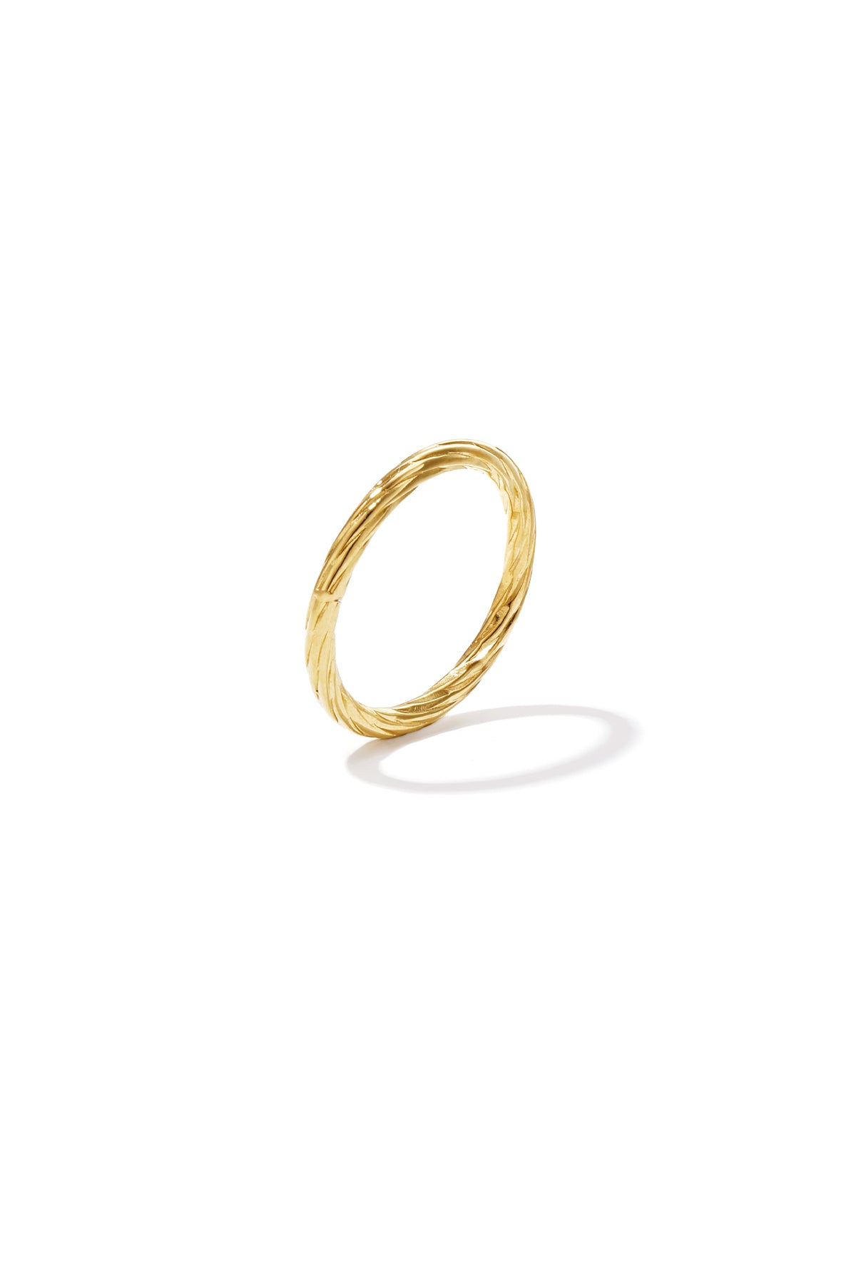 Close-up of a delicate twisted gold ring on white background