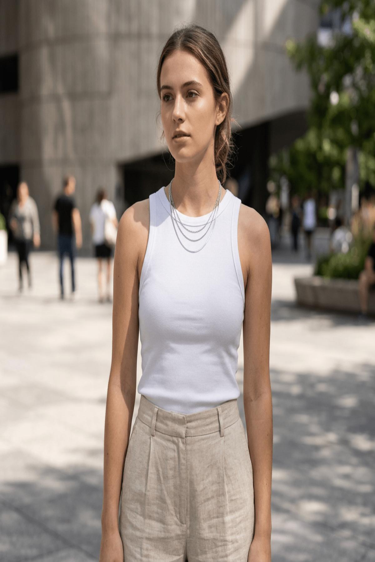 Full-length view of a model wearing a layered gold chain necklace styled with casual outfit in an urban setting, showcasing its versatile length and trendy appeal.