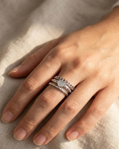Small Dainty Heart Chain ring on a model's hand resting on soft fabric, showcasing the delicate multi-layered heart design and sparkle in warm sunlight.