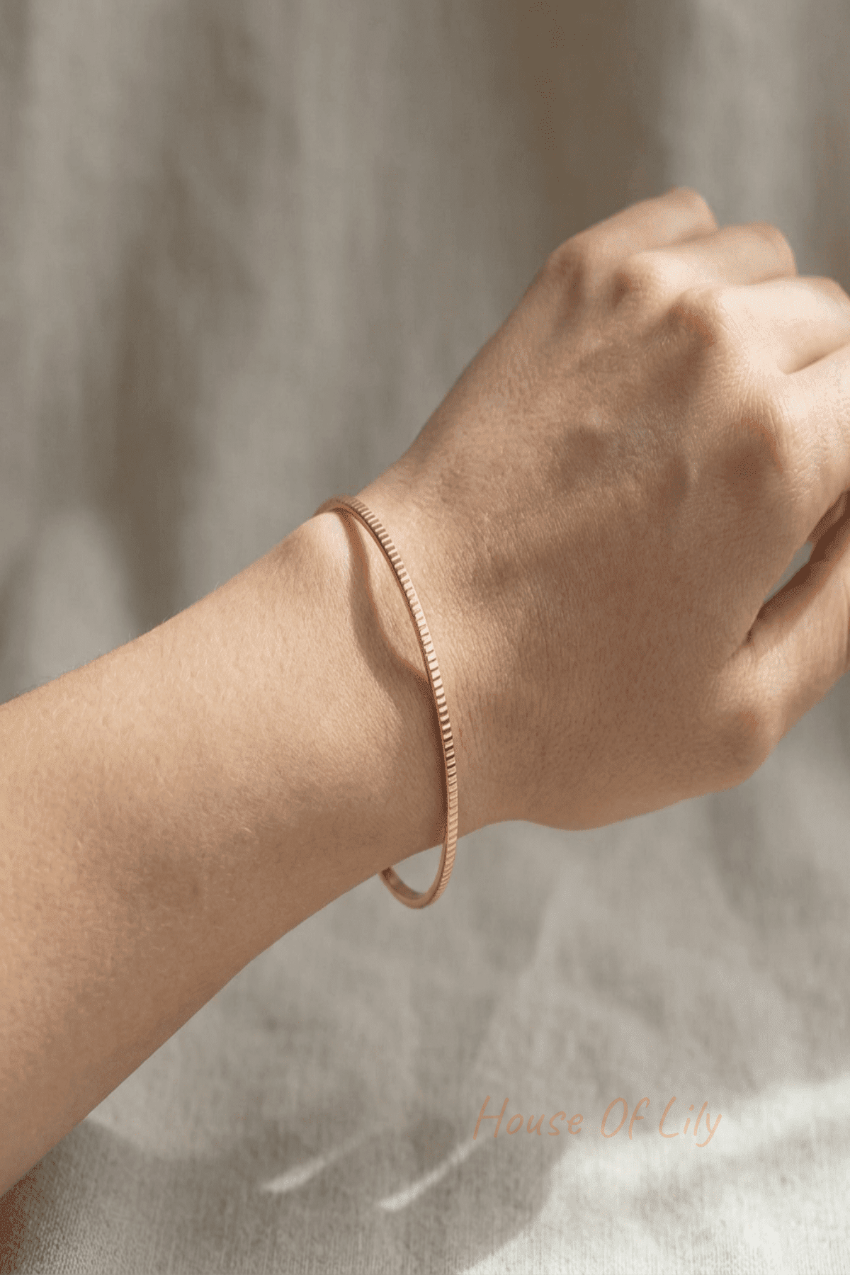 Model wears a minimalist stainless steel textured bangle showing its slim profile and ergonomic fit in natural light.