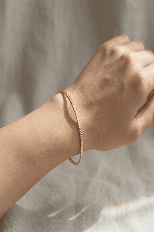Model wears a minimalist stainless steel textured bangle showing its slim profile and ergonomic fit in natural light.