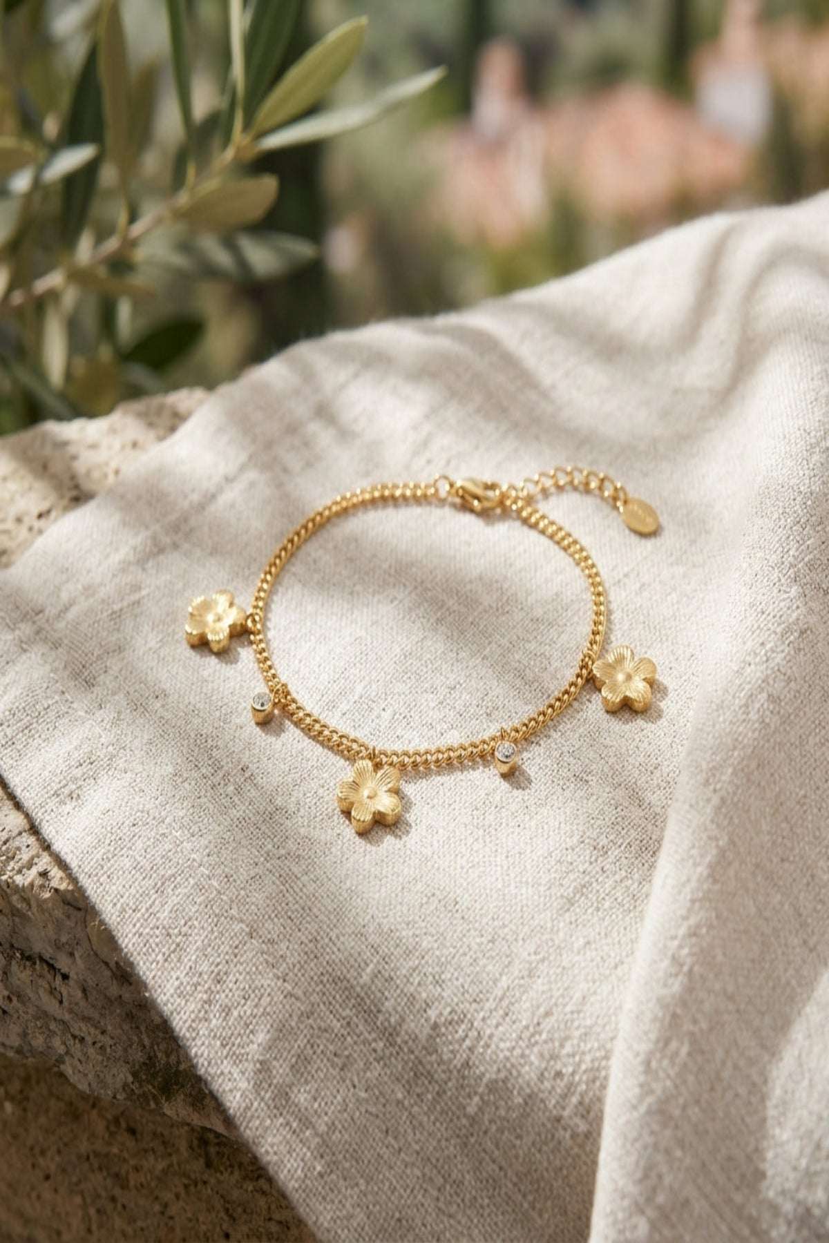 Small flower-shaped stainless steel bracelet resting on natural wood surface, showcasing its gleaming finish and delicate floral design.