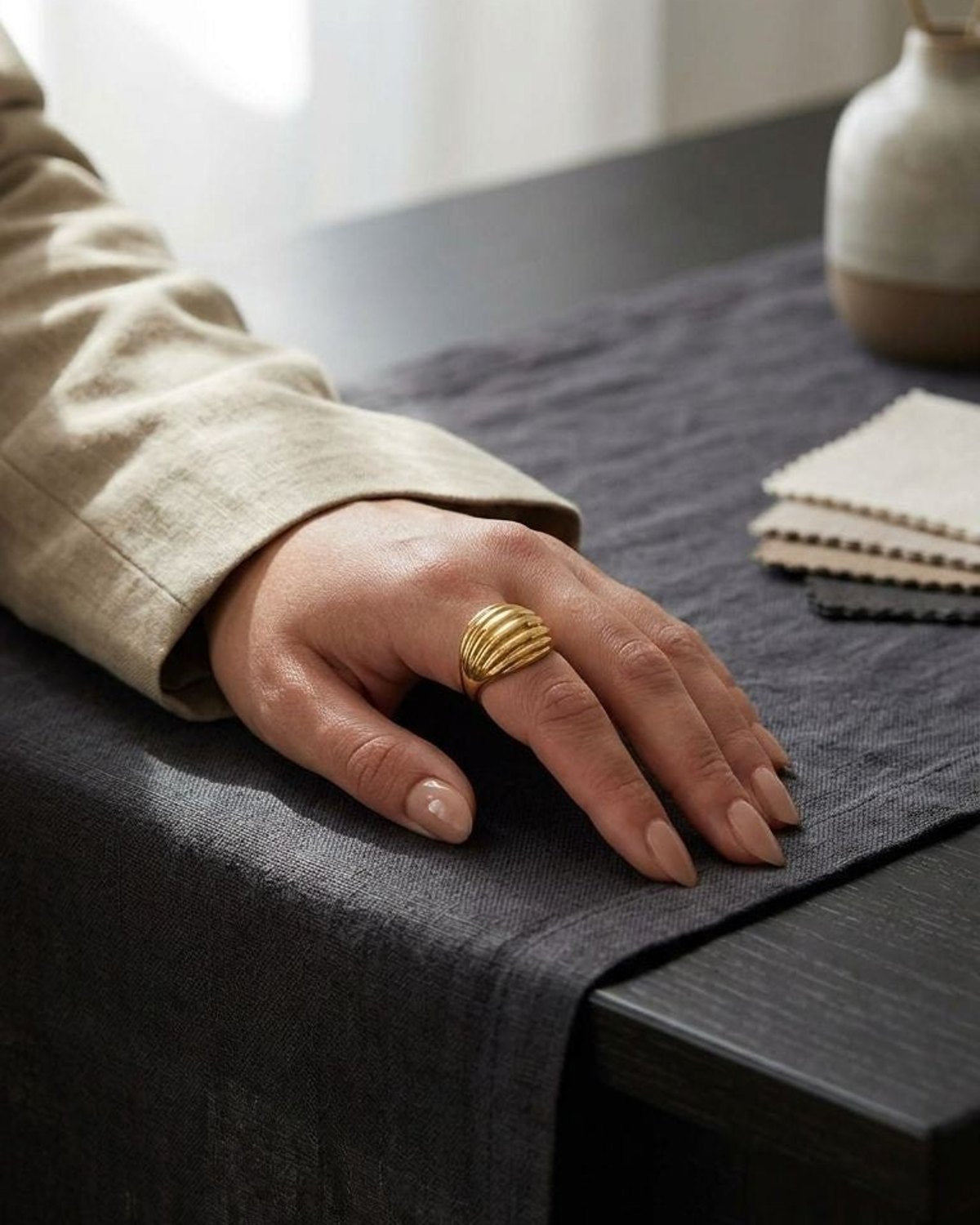 Small gold stainless steel statement ring with ribbed silhouette, resting on black velvet cushion, highlighting its textured pattern and irregular shape.