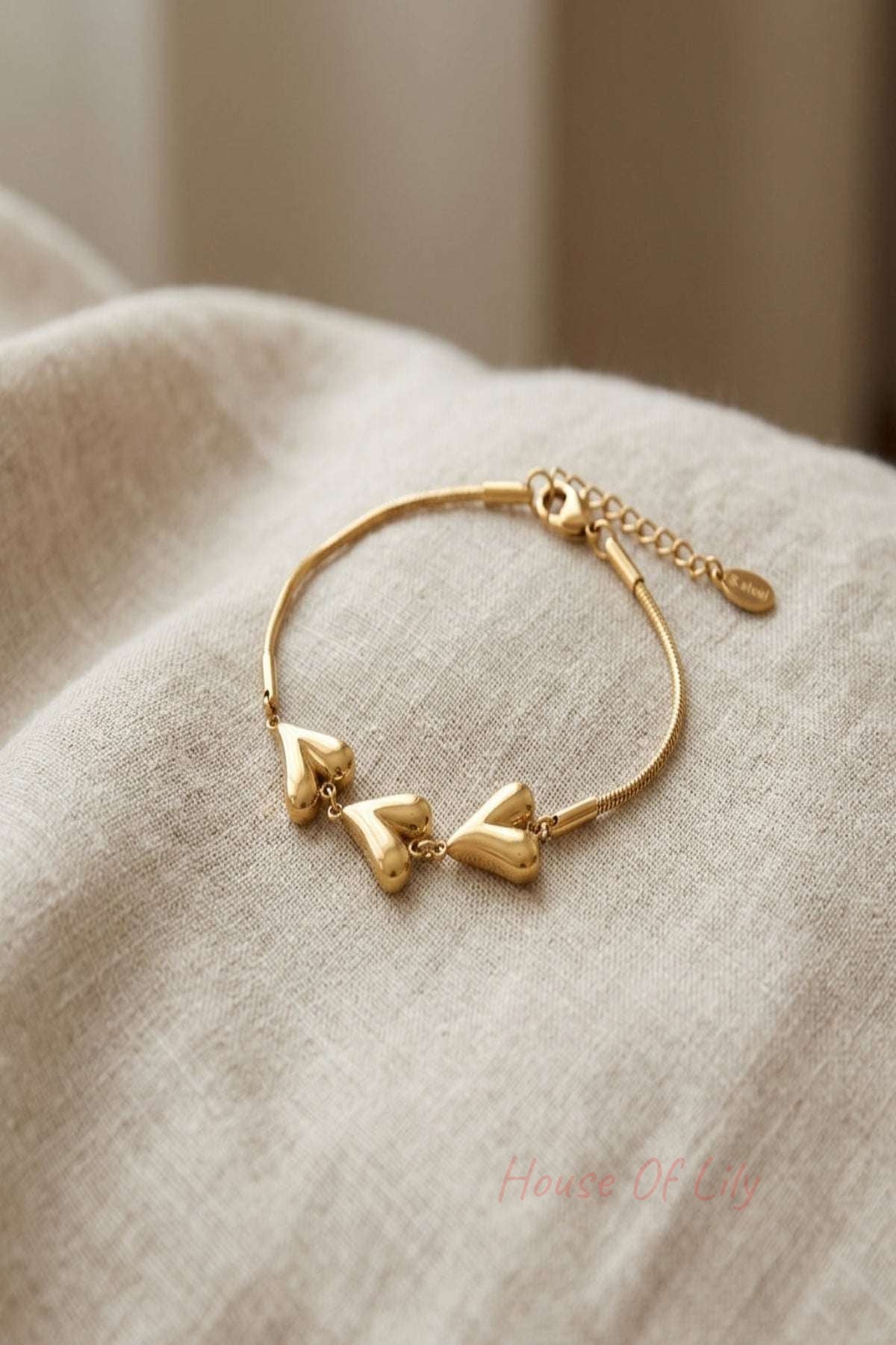 Close-up of hearts unfolded bracelet with heart-shaped links on textured surface, highlighting its stainless steel shine and delicate design.