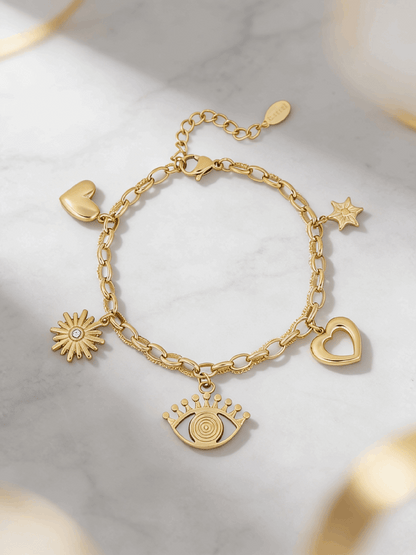 Gold charm bracelet featuring evil eye, heart, sun, and star charms on a textured link chain against marble.
