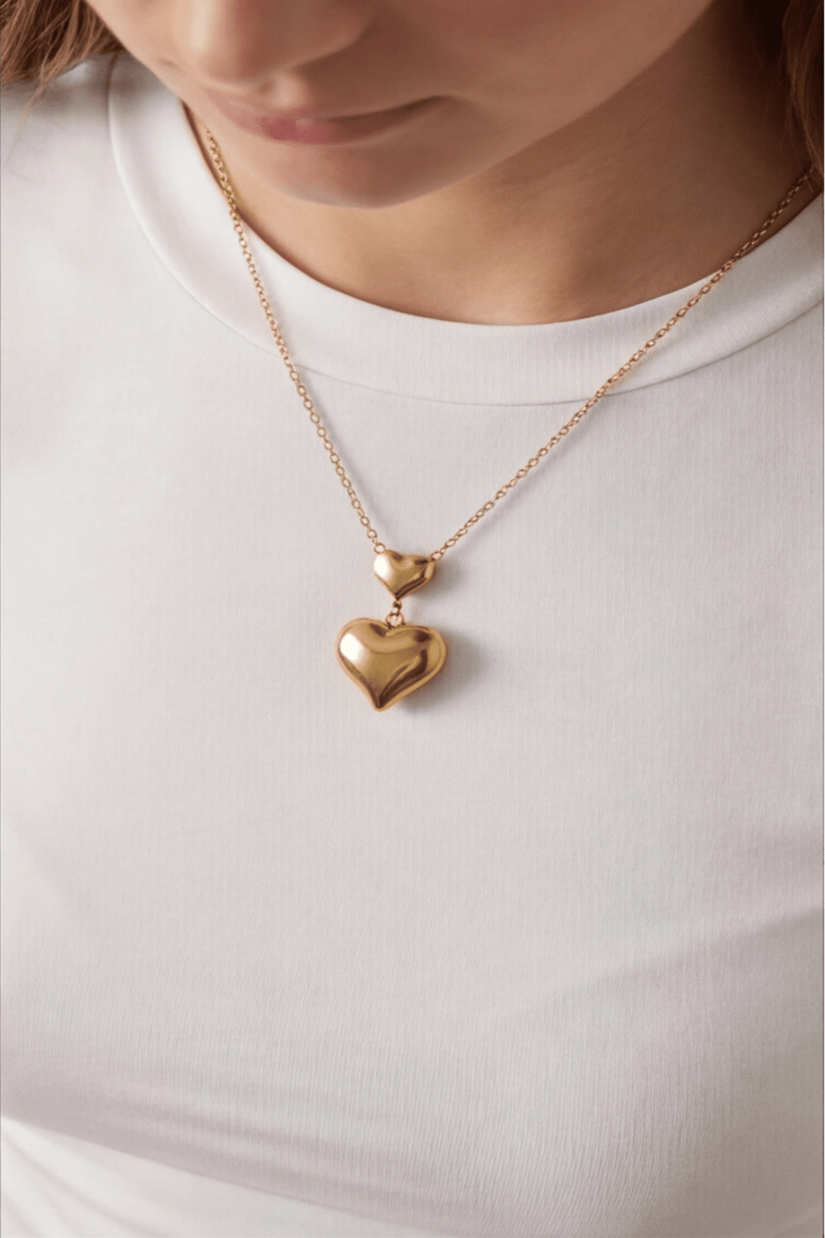 Gold heart-shaped pendant necklace on a white shirt